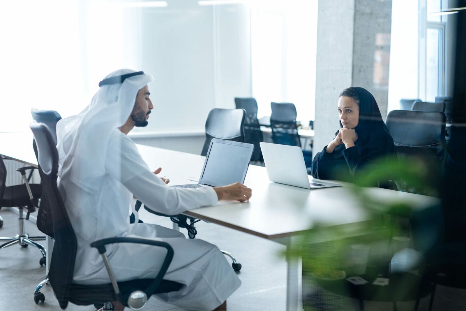 Two colleagues reviewing a project on laptops